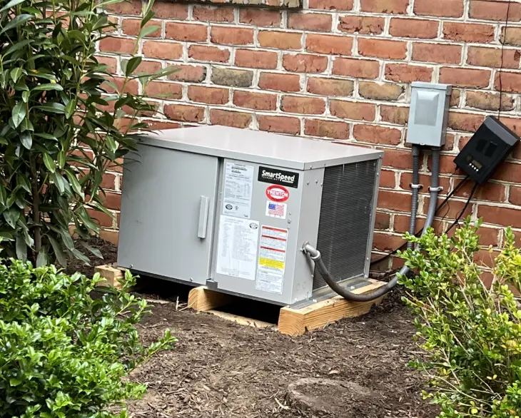 A small air conditioner is sitting outside in the dirt.